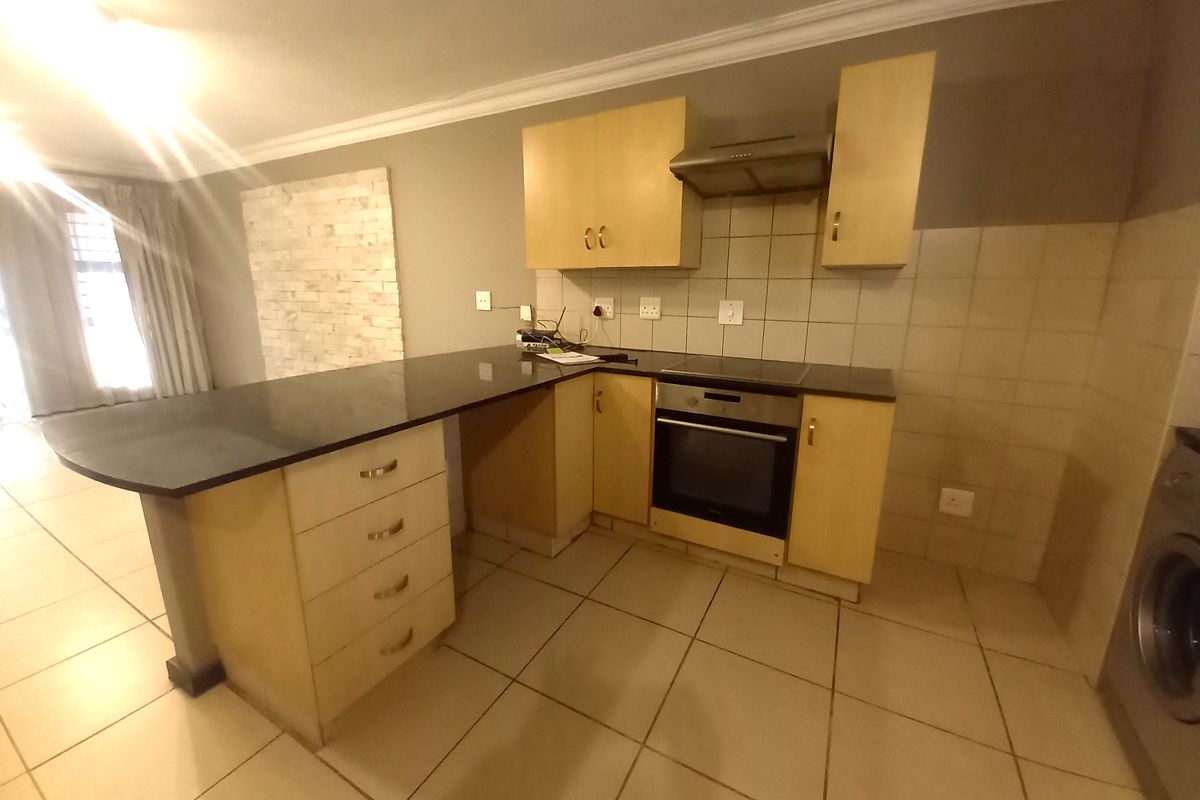 A functional kitchen featuring light wood cabinetry, granite countertops, a breakfast bar, and built-in appliances including an oven and hob.