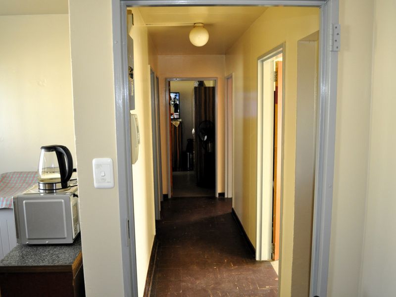 A functional hallway connecting multiple rooms, featuring dark flooring and neutral wall tones, providing access to the apartment's interior layout.