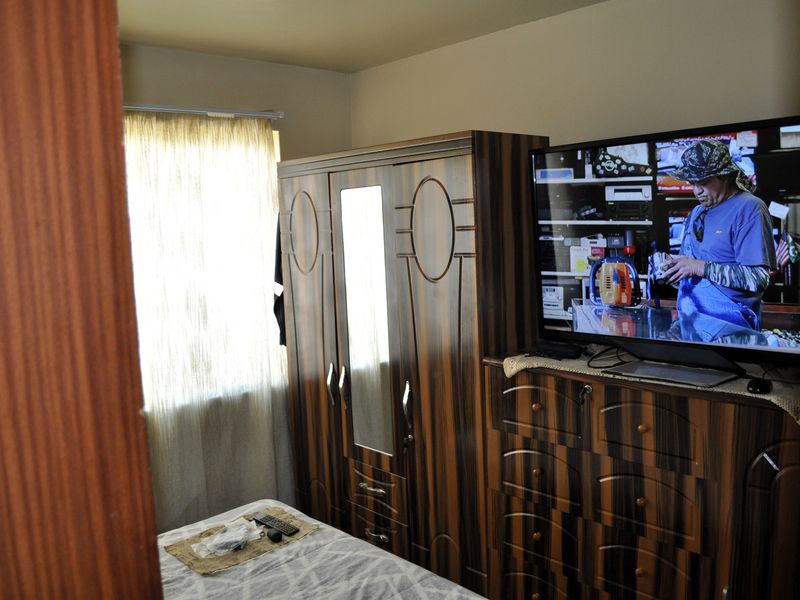 A bedroom featuring a window with curtains and space for storage furniture.