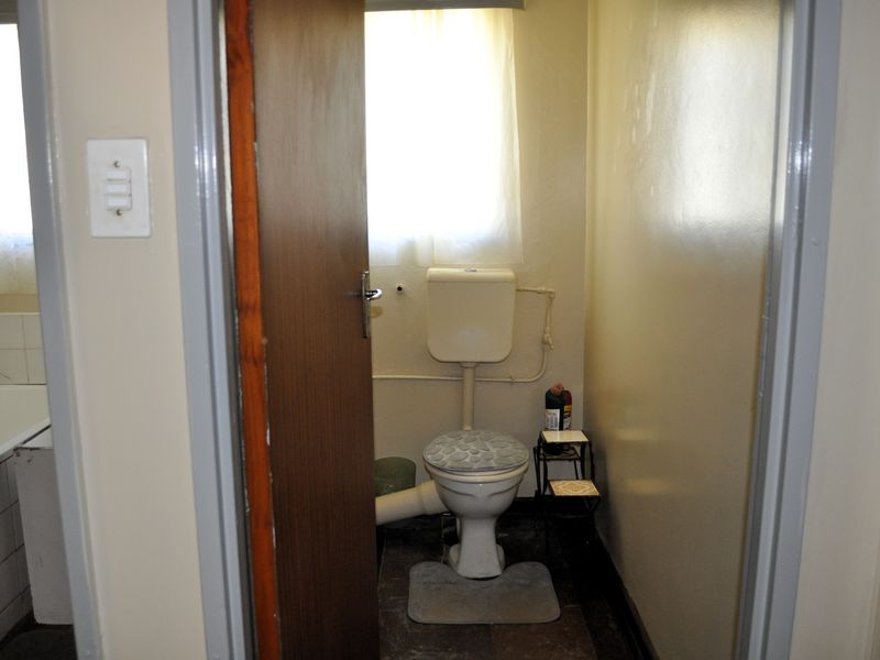 A functional bathroom featuring a standard toilet and bathtub with tiled splashback, requiring cosmetic updates to improve the overall aesthetic.