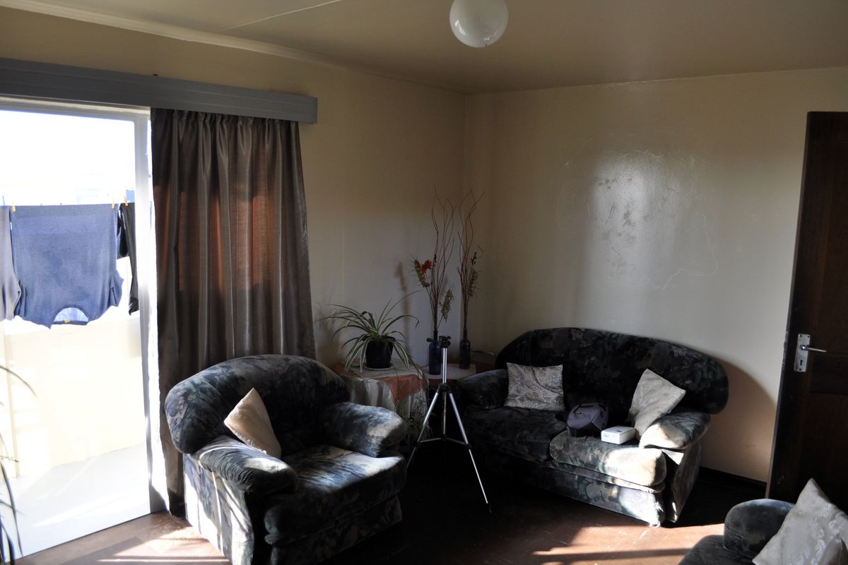 A living room area featuring a sliding glass door with access to an outdoor space, requiring cosmetic updates to the wall finishes.