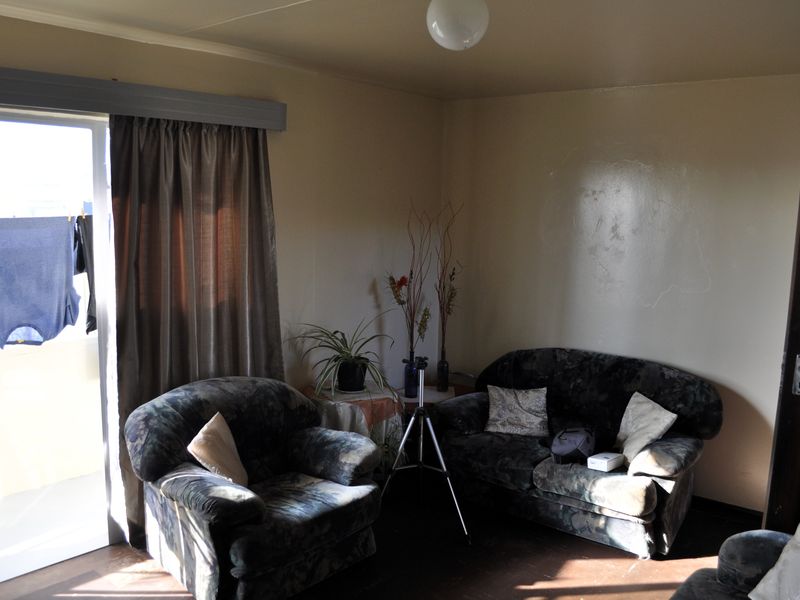 A living room area featuring a sliding glass door with access to an outdoor space, requiring cosmetic updates to the wall finishes.