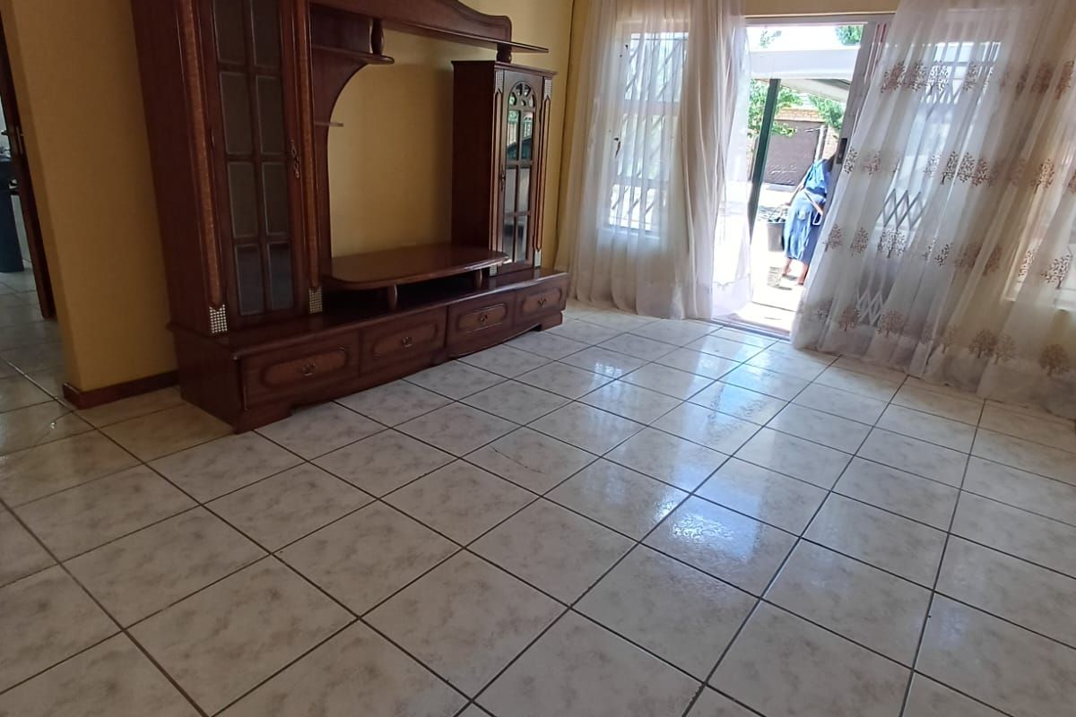 A living room featuring light-colored tiled flooring and a sliding glass door providing access to the outdoor area.