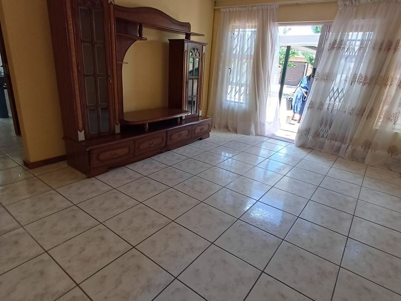 A living room featuring light-colored tiled flooring and a sliding glass door providing access to the outdoor area.