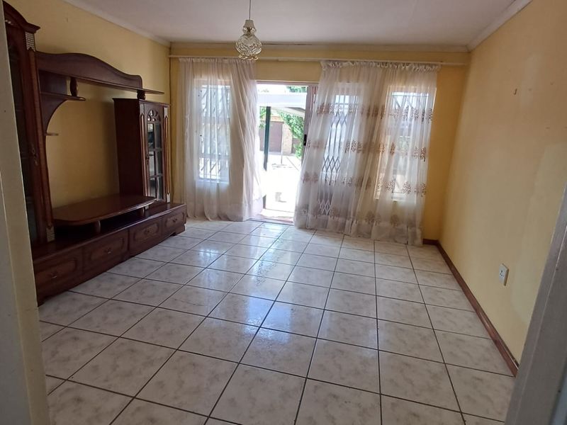 A living room featuring ceramic floor tiles, a sliding glass door with security gate, and access to an outdoor area.