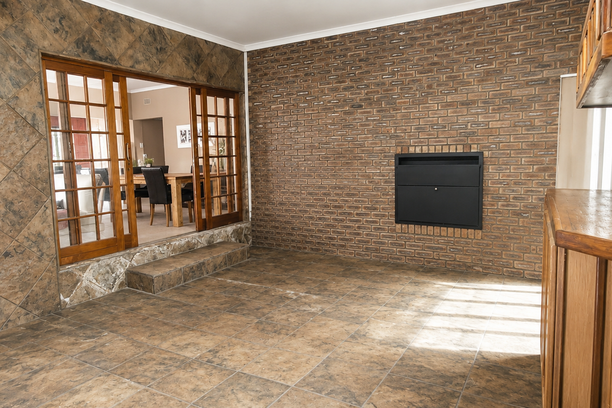 Spacious living area featuring a brick fireplace, tiled flooring, and sliding wooden doors leading to an adjacent dining space.