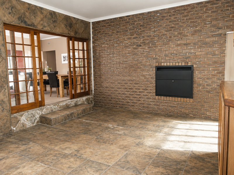Spacious living area featuring a brick fireplace, tiled flooring, and sliding wooden doors leading to an adjacent dining space.