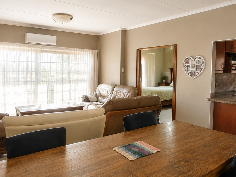 Open-plan living and dining area featuring a kitchen with granite breakfast bar, tiled floors, and direct access to the patio through sliding glass doors.