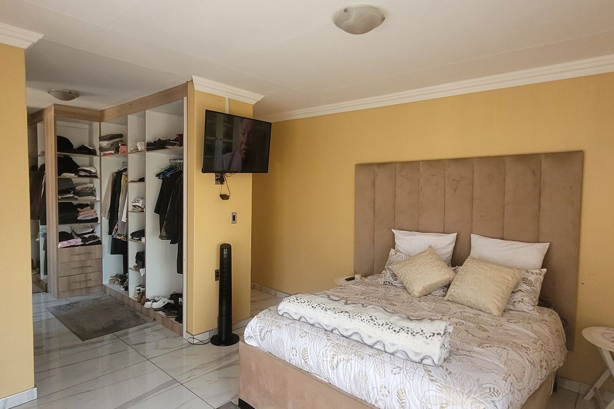 A bedroom featuring tiled flooring, crown molding, and an integrated open-concept built-in wardrobe area.