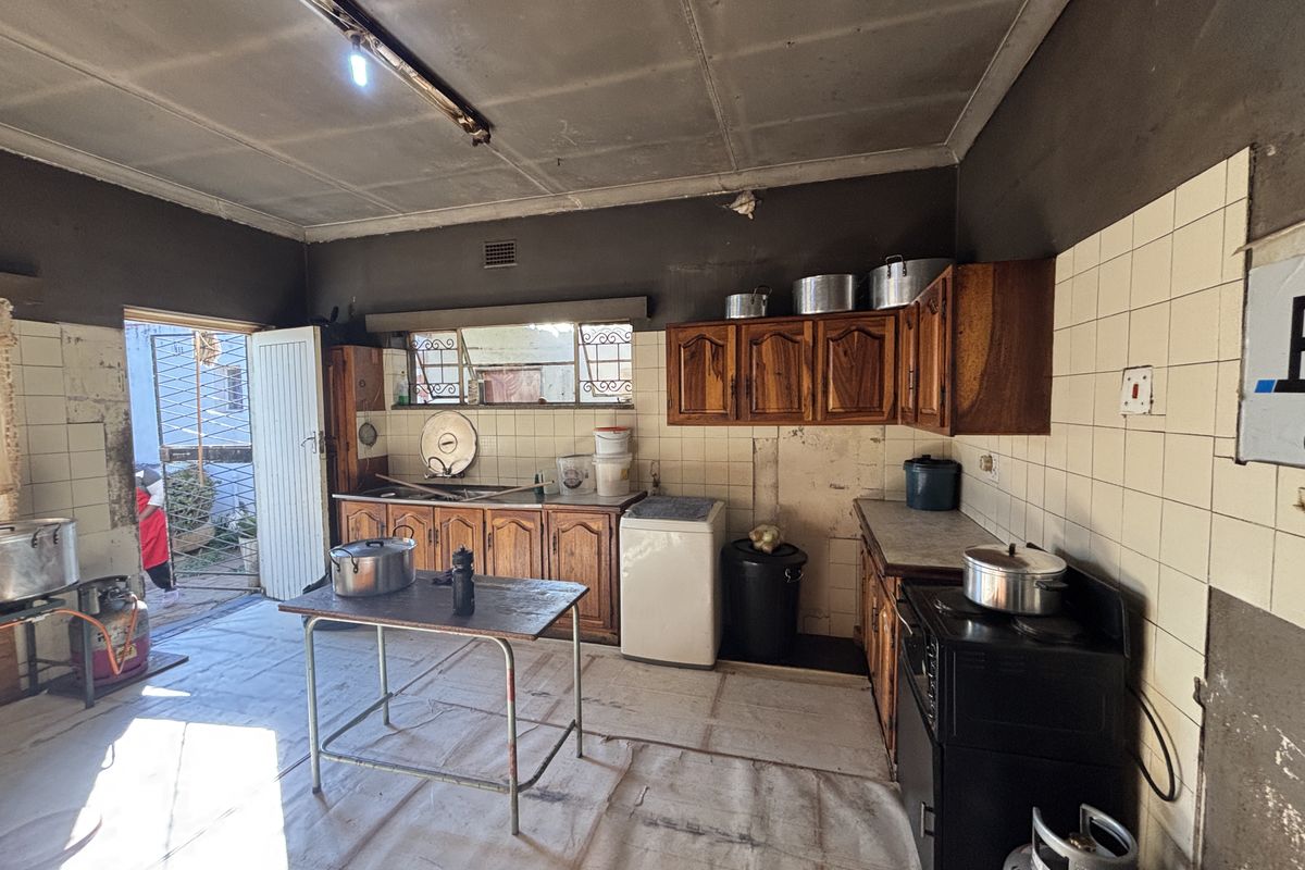 A dated kitchen featuring wooden cabinetry, tiled splashbacks, and a freestanding stove, requiring significant renovation and cosmetic updates to improve functionality and aesthetic appeal.
