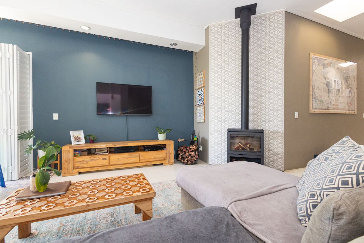 A well-maintained living room featuring a modern freestanding fireplace, tiled flooring, and a striking blue accent wall with recessed lighting.