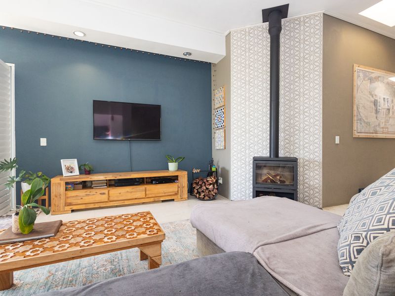 A well-maintained living room featuring a modern freestanding fireplace, tiled flooring, and a striking blue accent wall with recessed lighting.