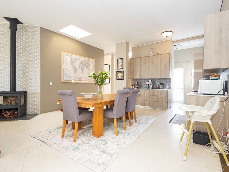 Open-plan living and dining area featuring a modern freestanding fireplace, skylight, and contemporary built-in cabinetry with neutral finishes.