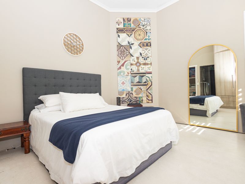 A well-maintained bedroom featuring neutral walls, built-in wardrobe storage, and plantation shutters, offering a clean and comfortable living space.