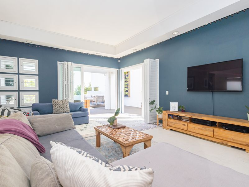 Spacious living room featuring a recessed ceiling, recessed lighting, and large bi-fold doors that open onto an outdoor patio area.