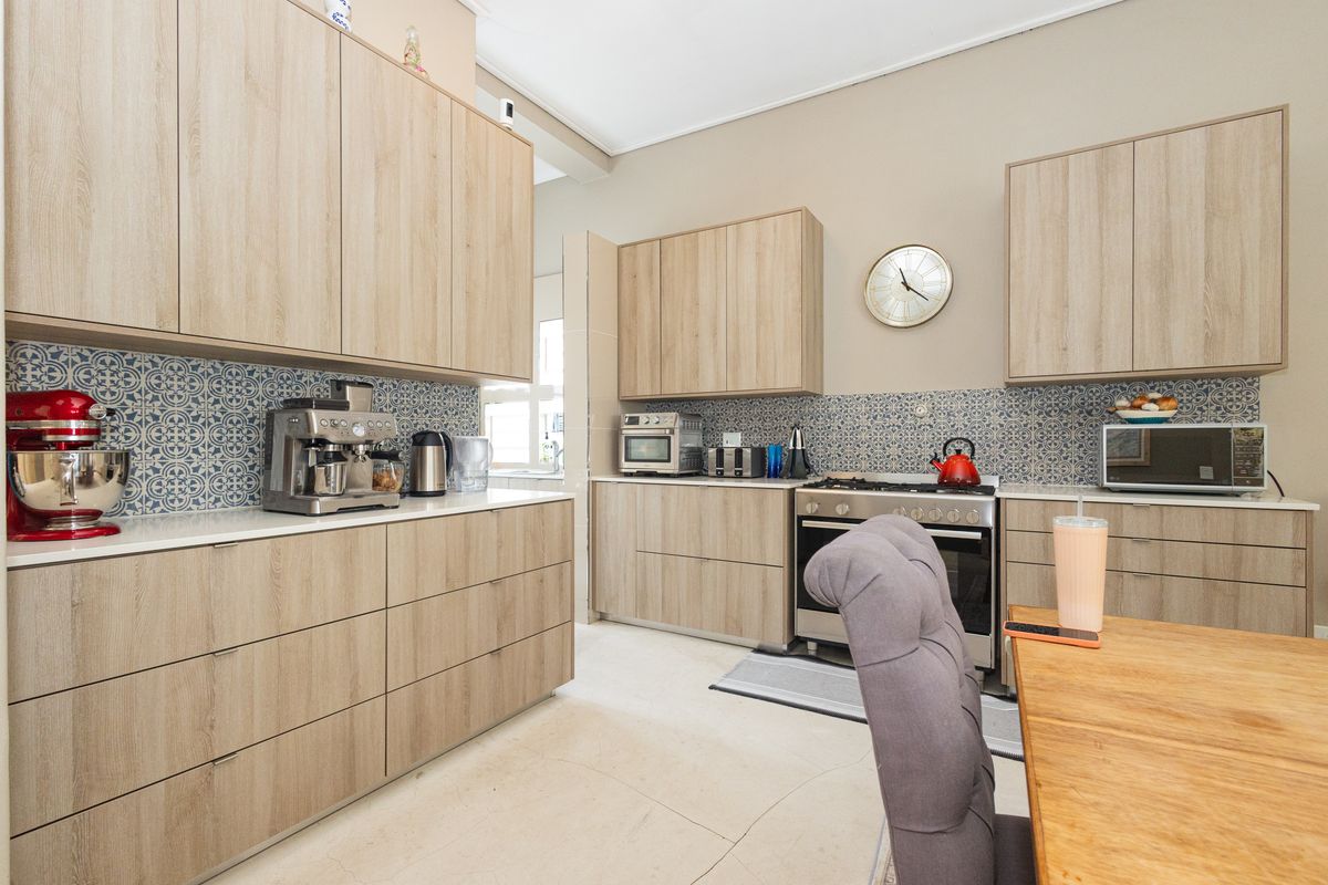 Modern kitchen featuring light wood-tone cabinetry, patterned tile backsplash, stone countertops, and a built-in gas stove with oven.