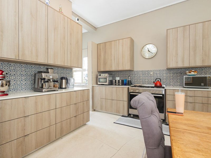 Modern kitchen featuring light wood-tone cabinetry, patterned tile backsplash, stone countertops, and a built-in gas stove with oven.
