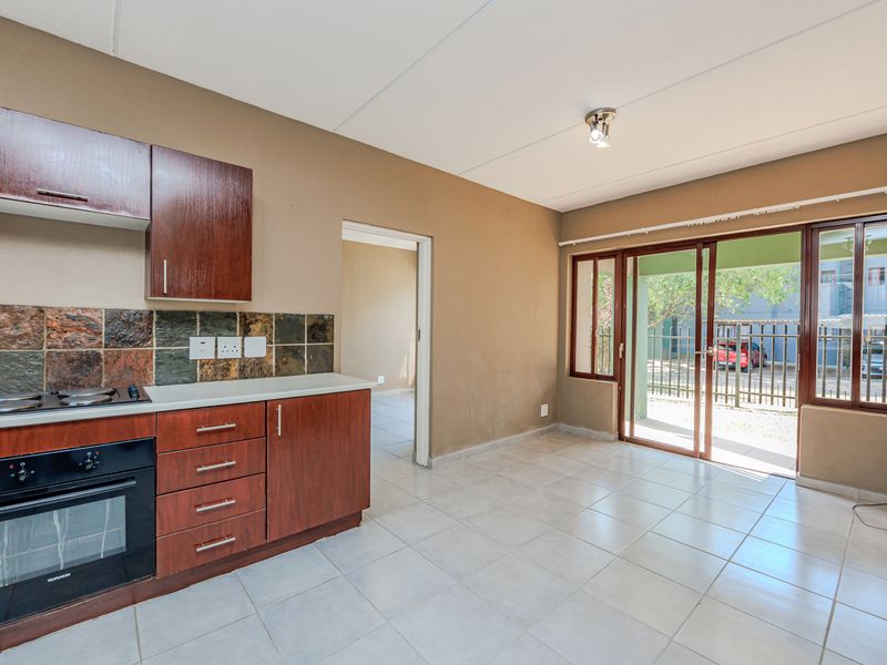 Open-plan kitchen and living area featuring tiled floors, built-in oven and hob, and sliding glass doors leading to an outdoor space.