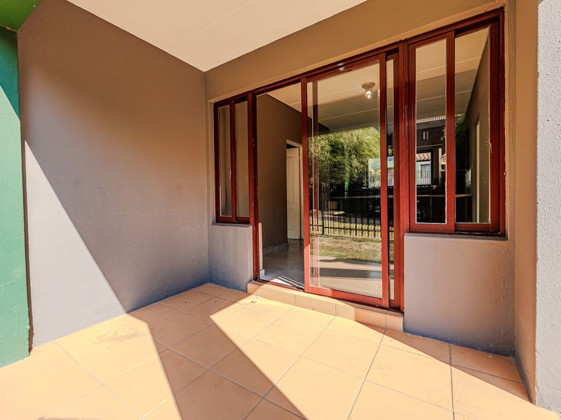 A clean, covered patio area featuring tiled flooring and large sliding glass doors providing access to the interior living space.