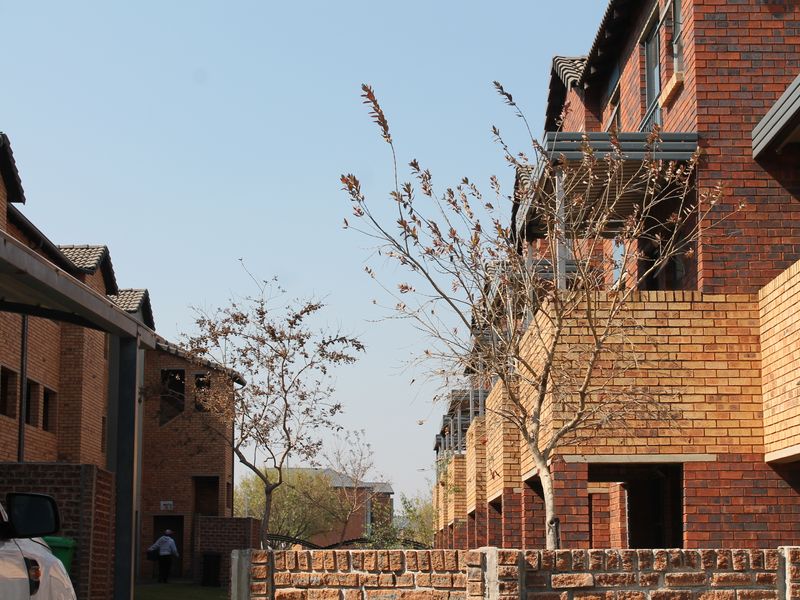 Exterior view of a multi-story apartment complex featuring face brick facades, tiled roofing, and private balconies.