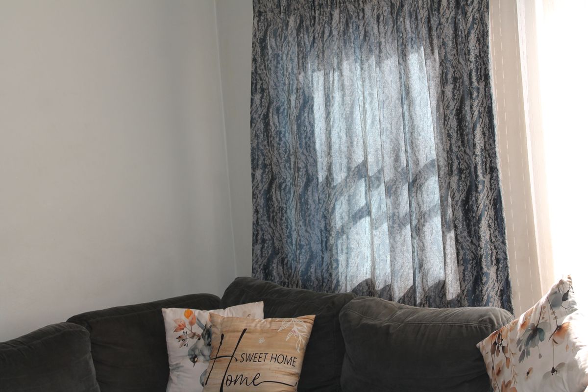 A view of a living room corner featuring a window with patterned curtains.