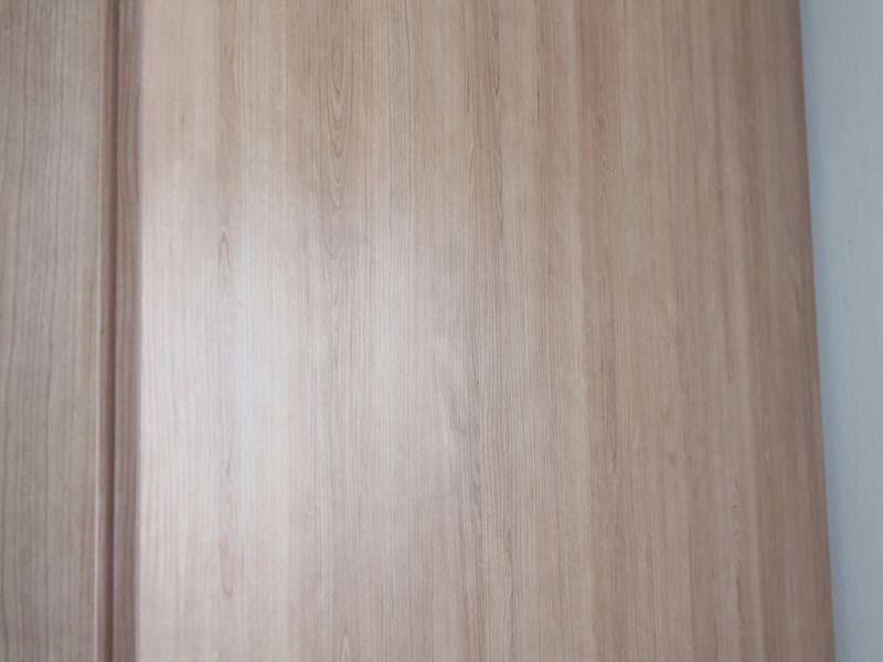A close-up view of light wood-grain built-in cabinetry or paneling.