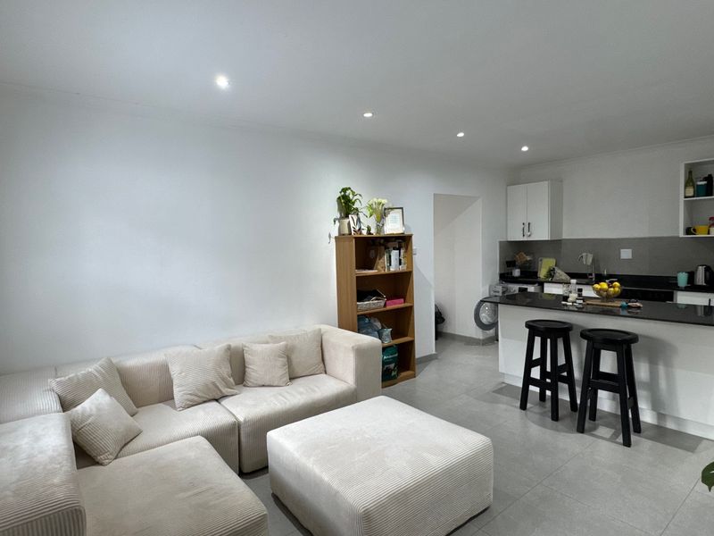 Open plan living area featuring a modern kitchen with granite countertops, breakfast bar, and neutral tiled flooring throughout.