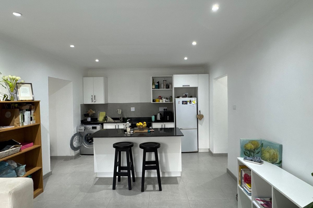 Modern kitchen featuring a central island with stone countertops, white cabinetry, recessed lighting, and tiled flooring in an open-plan layout.