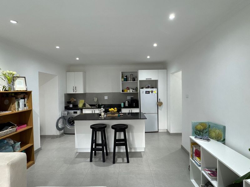 Modern kitchen featuring a central island with stone countertops, white cabinetry, recessed lighting, and tiled flooring in an open-plan layout.