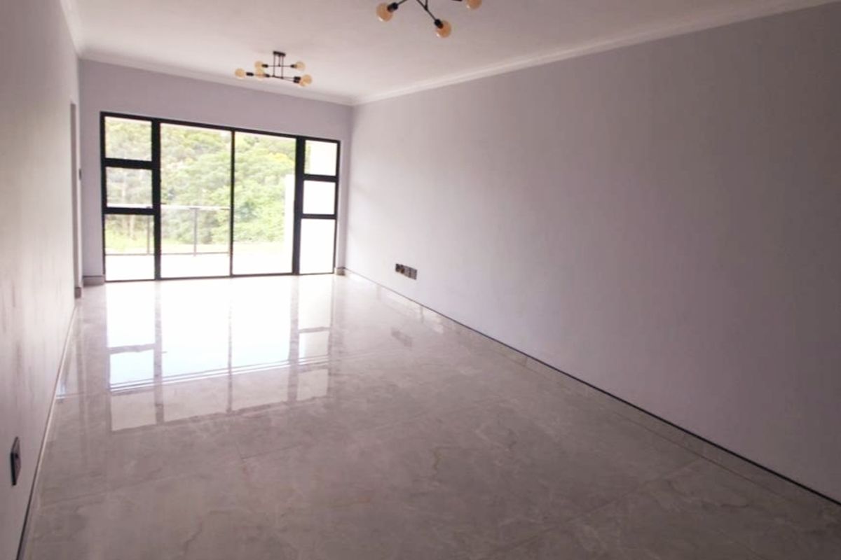 A bright, spacious, and empty living area featuring polished tiled floors, modern light fixtures, and large sliding glass doors leading to an outdoor space.