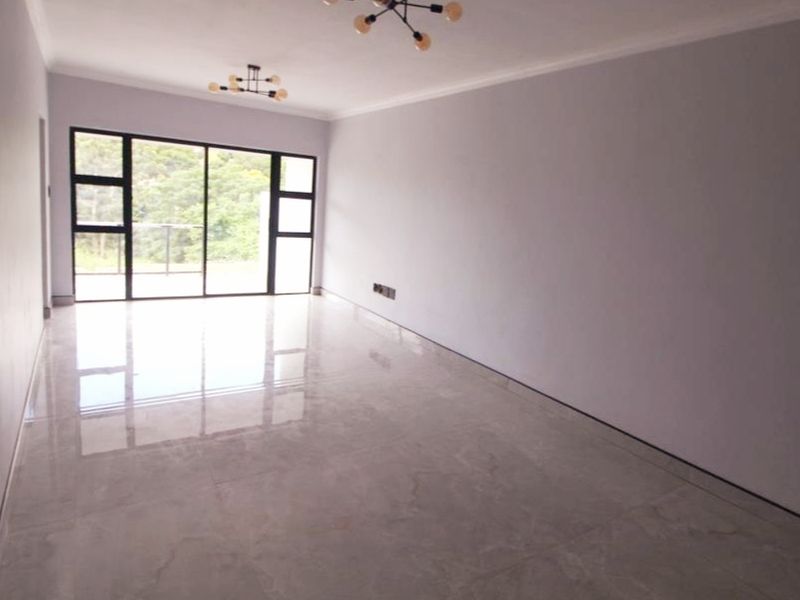 A bright, spacious, and empty living area featuring polished tiled floors, modern light fixtures, and large sliding glass doors leading to an outdoor space.