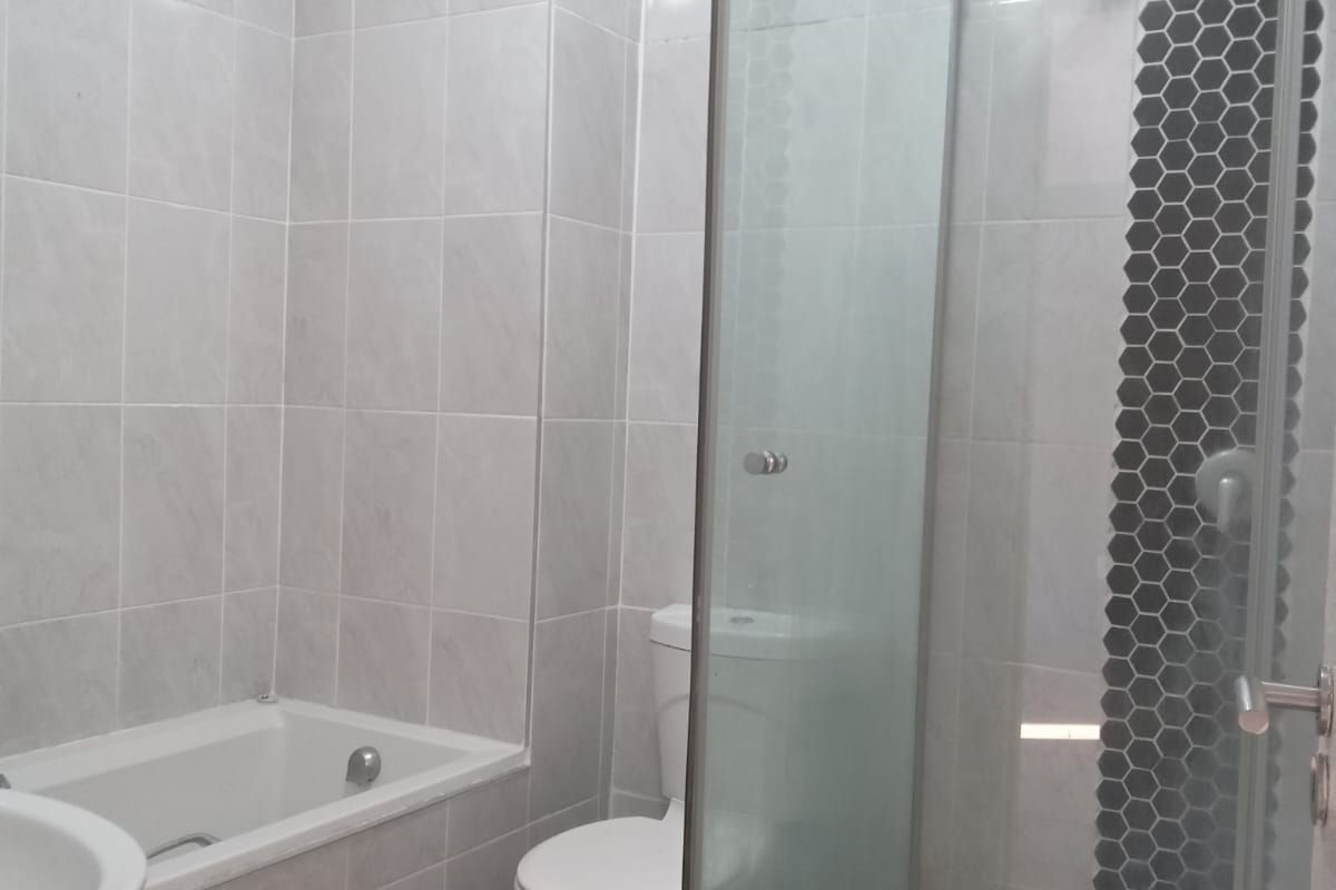 A modern bathroom featuring a built-in bathtub, a separate glass-enclosed shower with mosaic accent tiling, a toilet, and a washbasin.