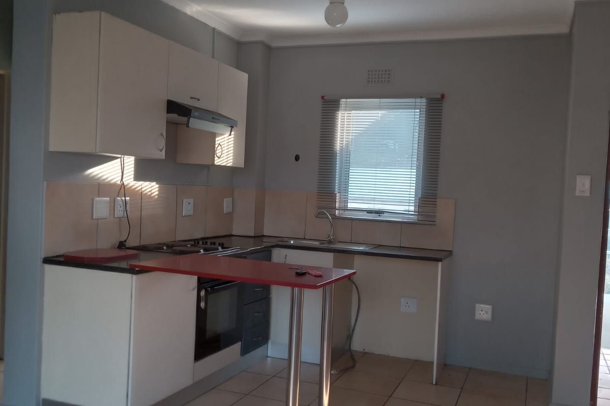 A functional kitchen featuring built-in cabinetry, a stainless steel sink, integrated oven, and tiled flooring, offering a clean and practical layout.