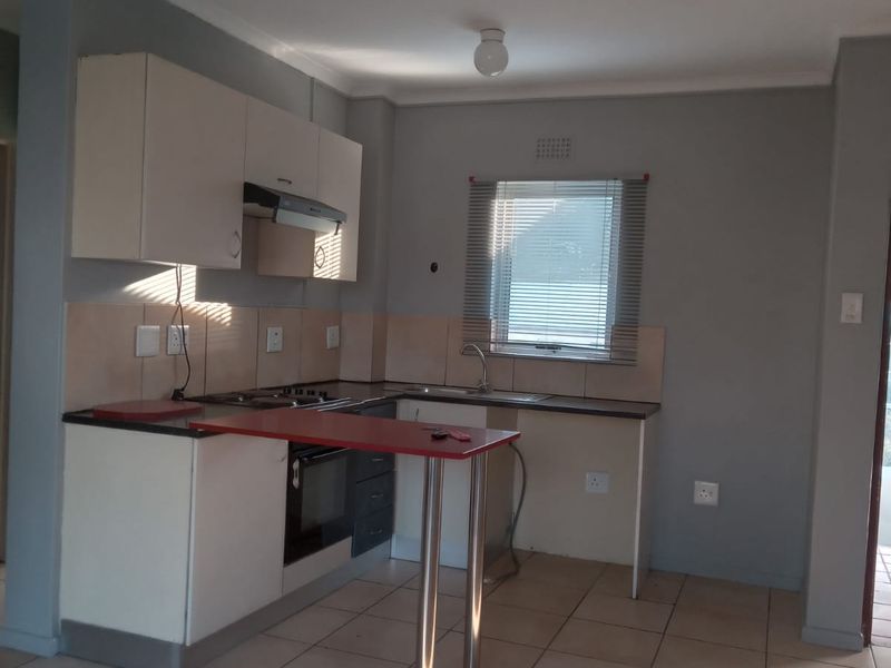 A functional kitchen featuring built-in cabinetry, a stainless steel sink, integrated oven, and tiled flooring, offering a clean and practical layout.