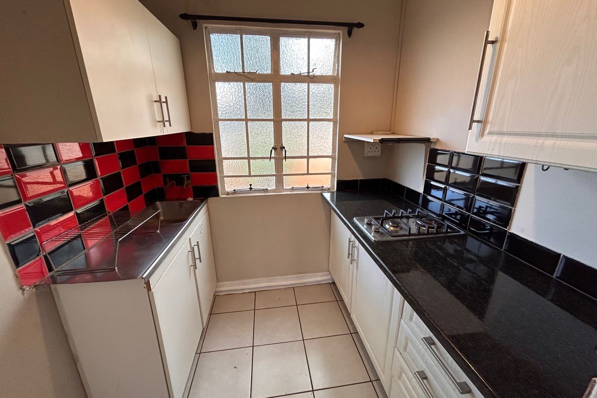 Compact kitchen featuring granite countertops, a gas hob, tiled splashbacks, and built-in cabinetry with tiled flooring.