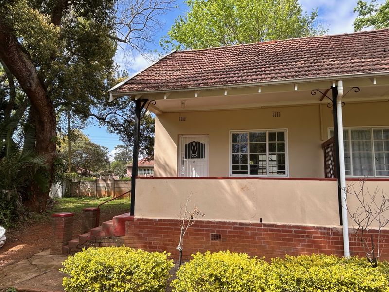 Front elevation of a flat featuring a covered porch, brick base, tiled roof, and security gate entrance.