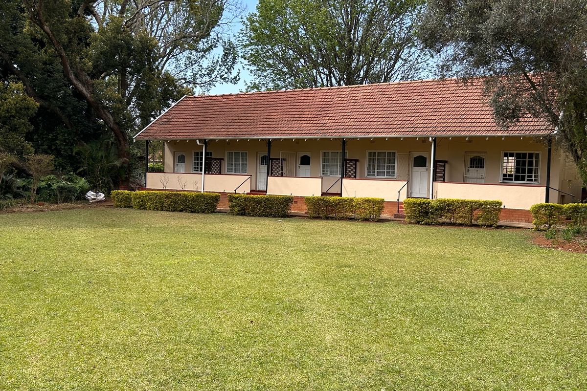 A view of the rear elevation of the flat, featuring a covered veranda, terracotta tiled roof, and a well-maintained garden area.