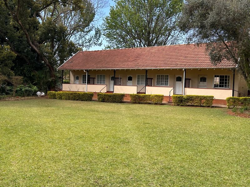 A view of the rear elevation of the flat, featuring a covered veranda, terracotta tiled roof, and a well-maintained garden area.