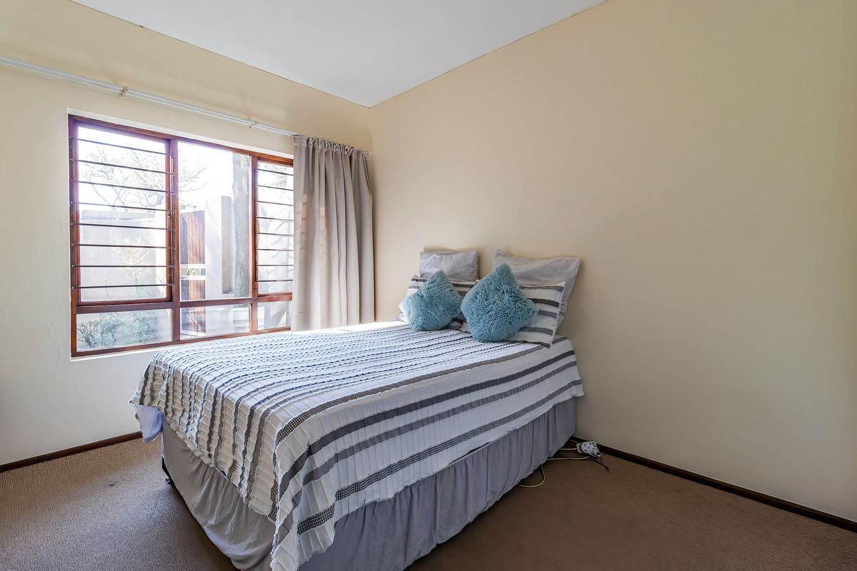 A functional bedroom featuring carpet flooring and a timber-framed window with security bars, offering a neutral canvas for potential updates.