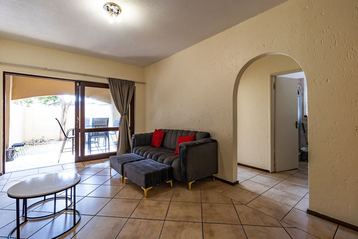 Living room featuring tiled flooring, an arched entryway, and a sliding glass door providing access to an outdoor patio area.