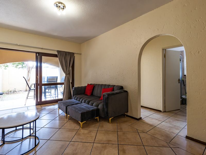Living room featuring tiled flooring, an arched entryway, and a sliding glass door providing access to an outdoor patio area.