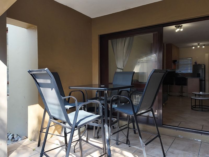 A covered patio area featuring tiled flooring and a large sliding glass door providing access to the interior living space.