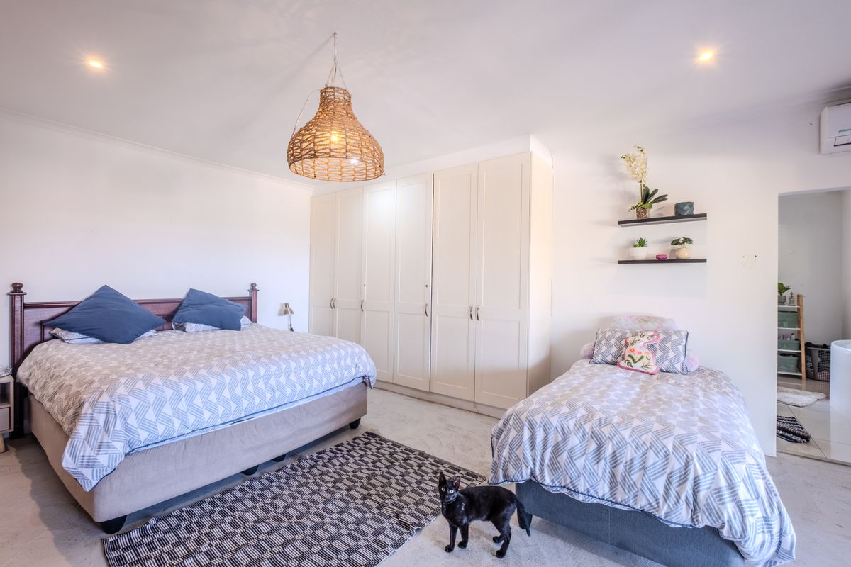Spacious bedroom featuring extensive built-in cabinetry, recessed lighting, and a wall-mounted air conditioning unit, providing ample storage and climate control.