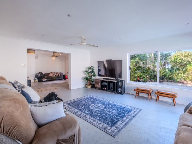 Spacious living room featuring concrete flooring, recessed lighting, a ceiling fan, and large sliding glass doors providing views of the garden.