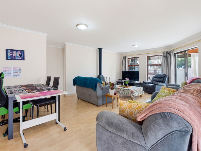 Spacious living area featuring laminate flooring and a central freestanding fireplace, with direct access to the outdoor area through sliding glass doors.