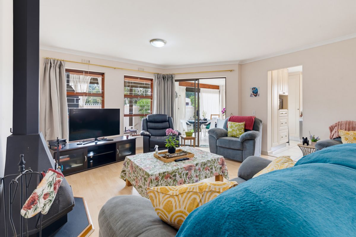 A comfortable living room featuring a freestanding fireplace, laminate flooring, and sliding glass doors that provide access to the patio area.