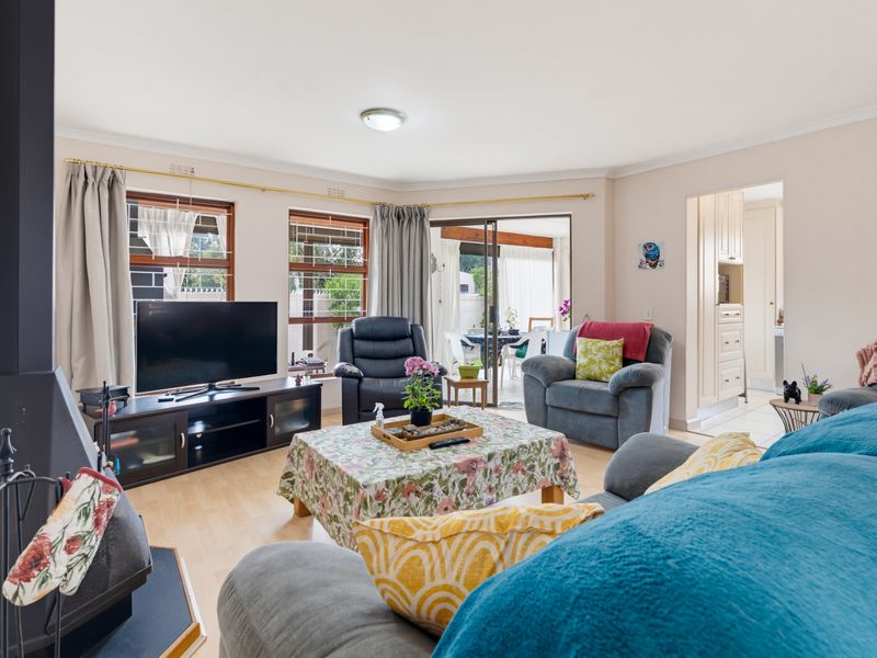 A comfortable living room featuring a freestanding fireplace, laminate flooring, and sliding glass doors that provide access to the patio area.