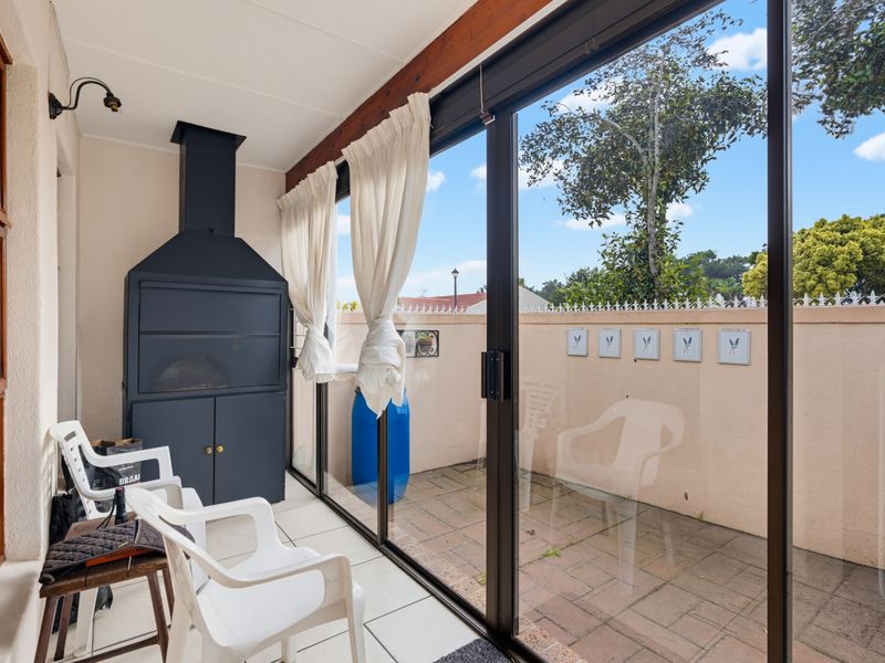 Enclosed patio area featuring a built-in braai, tiled flooring, and large sliding glass doors providing access to the outdoor space.