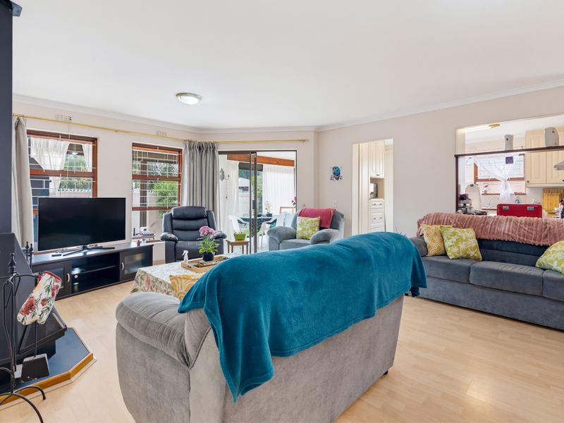 Spacious living room featuring laminate flooring, a freestanding fireplace, and a convenient pass-through window connecting to the kitchen area.