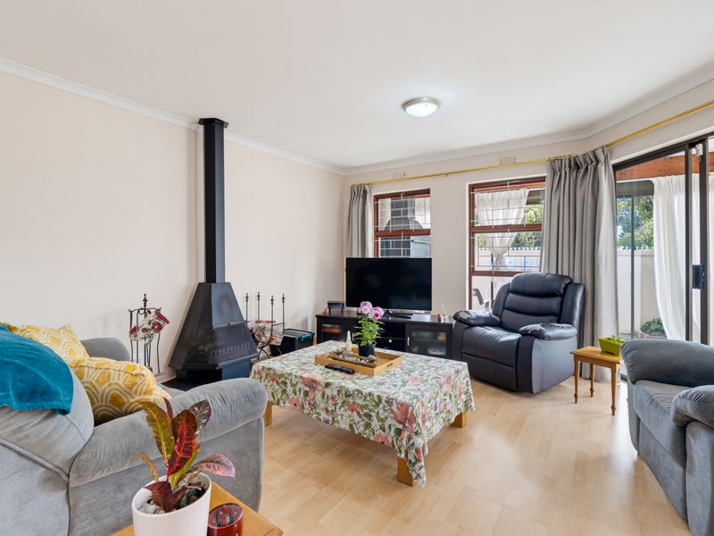 A comfortable living room featuring laminate flooring, a freestanding fireplace, and sliding glass doors providing access to the outdoor area.
